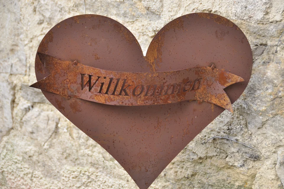 Herzförmiges Willkommensschild an einer Steinwand