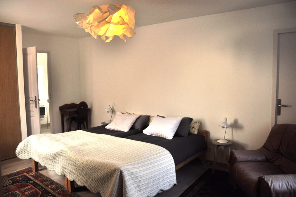 Gästezimmer mit Doppelbett, weisser Bettdecke und Holzboden