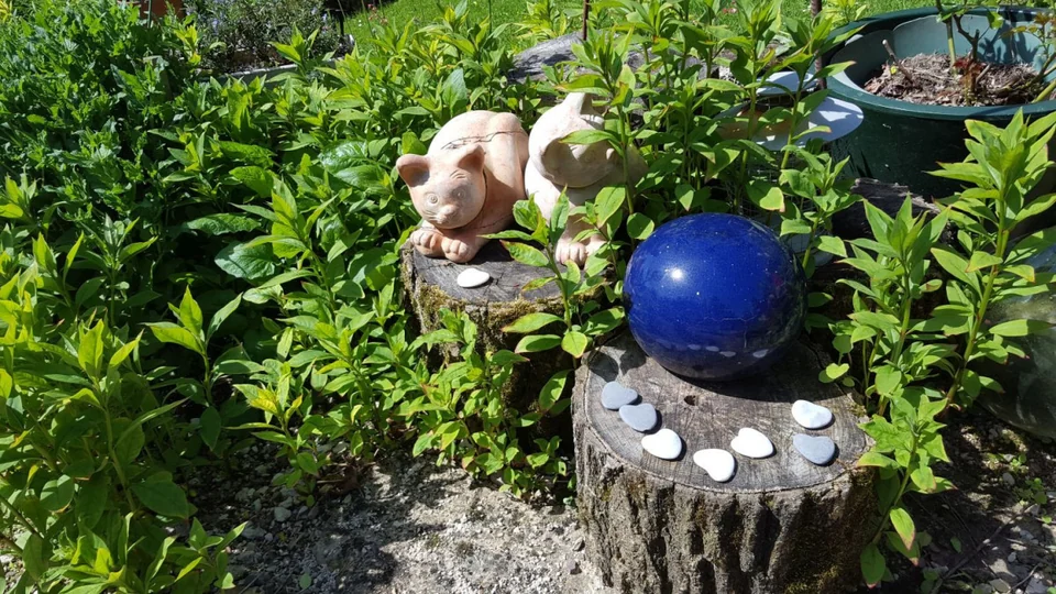 Gartendekoration mit blauer Glaskugel und Figuren